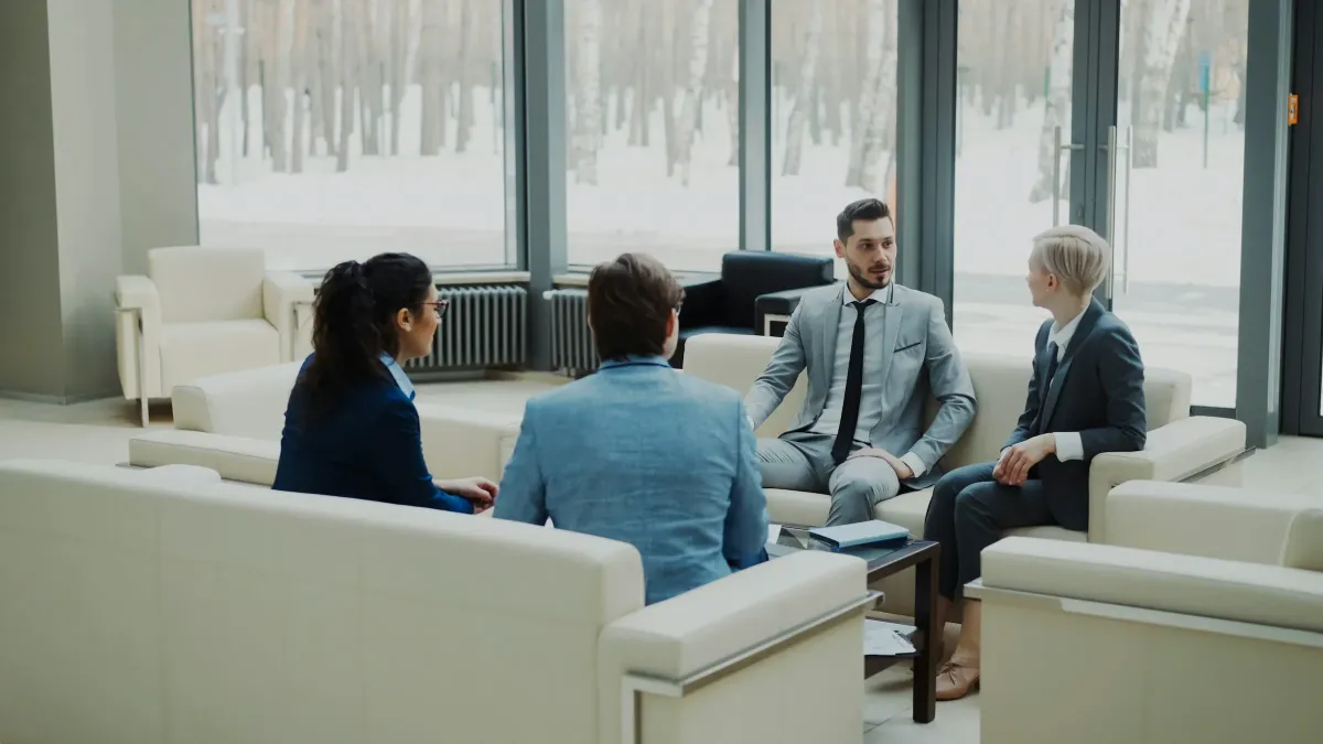 Four professionals in conversation in a meeting lounge