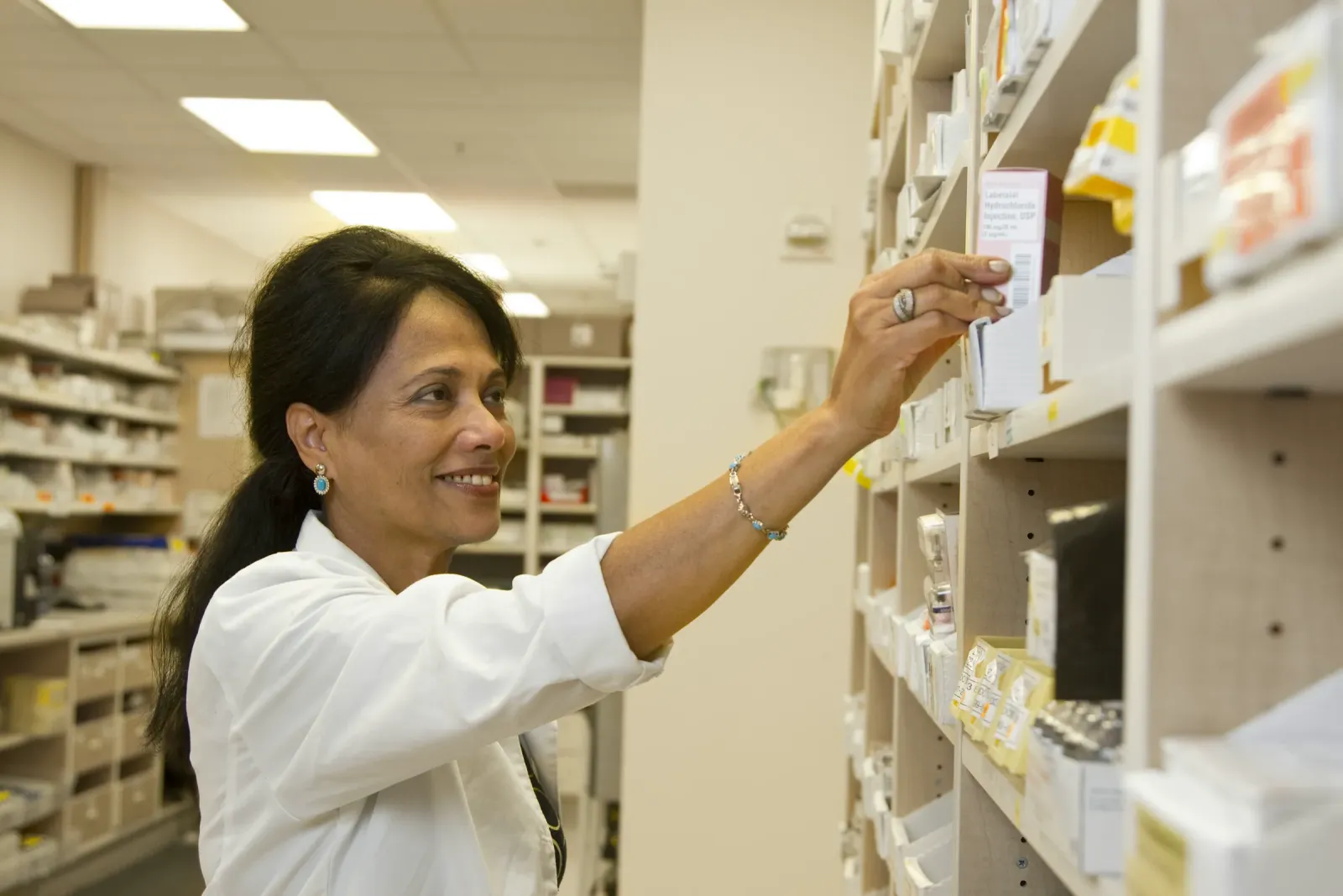 A pharmacist taking a medicine box from a shelf
